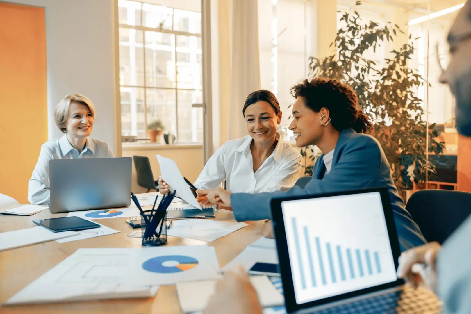 Three professionals discussing data in a bright office meeting.